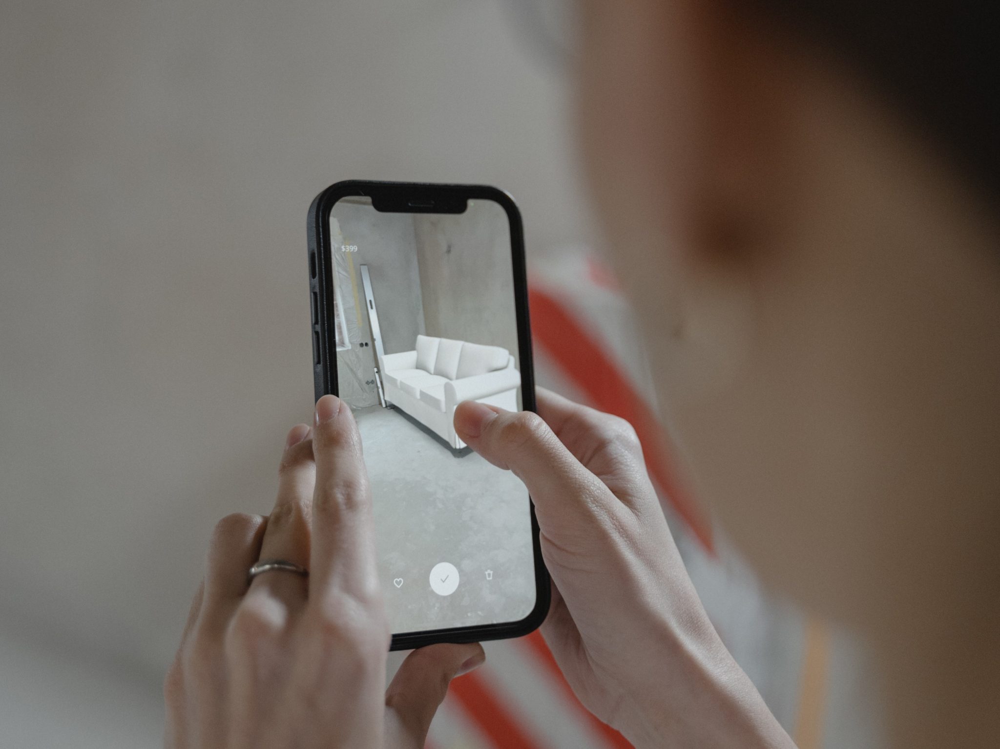 A close up of a phone screen showing how a couch would look in an empty room.