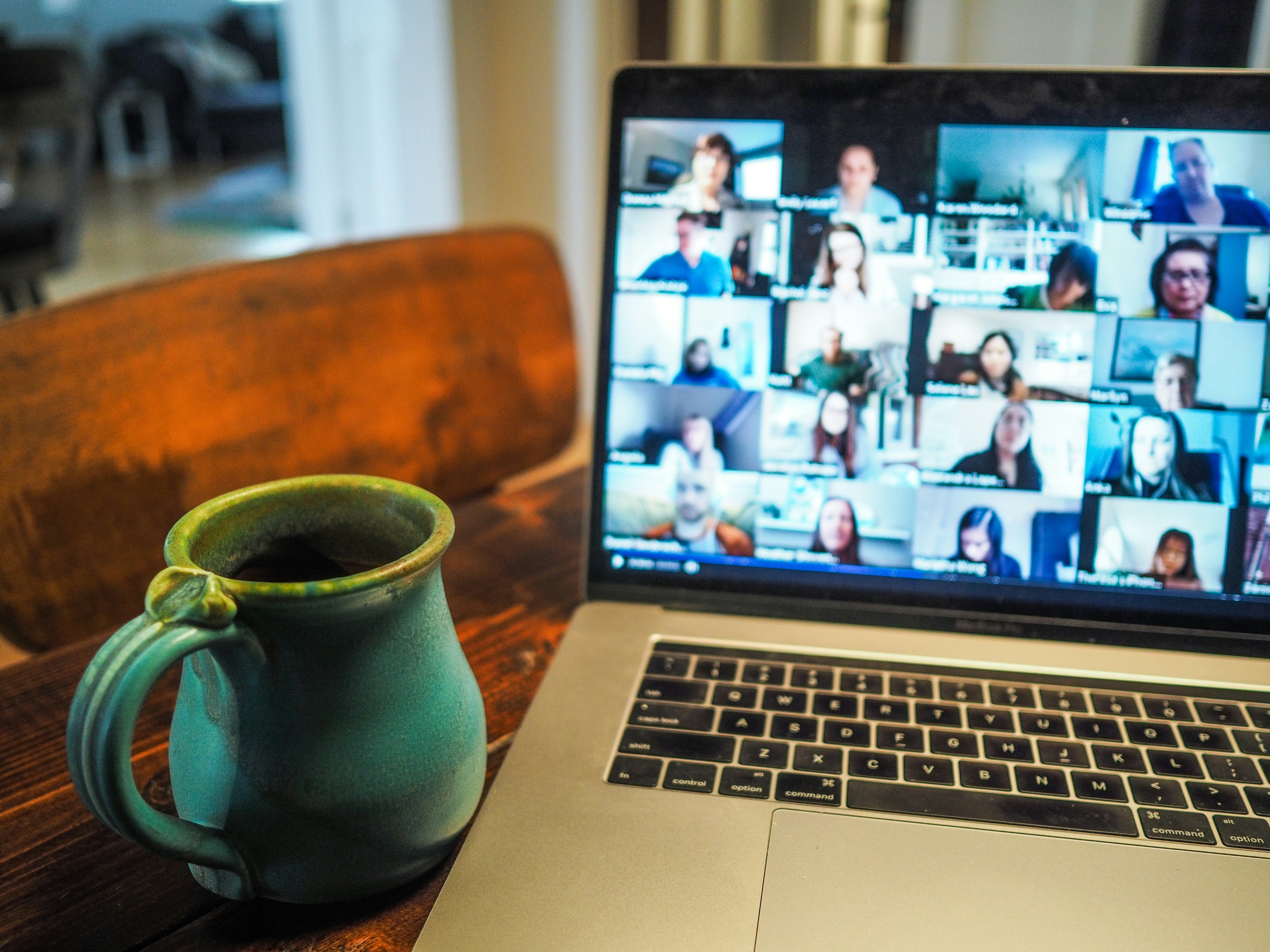 Image of a laptop with multiple people on a video call next to a coffee mug