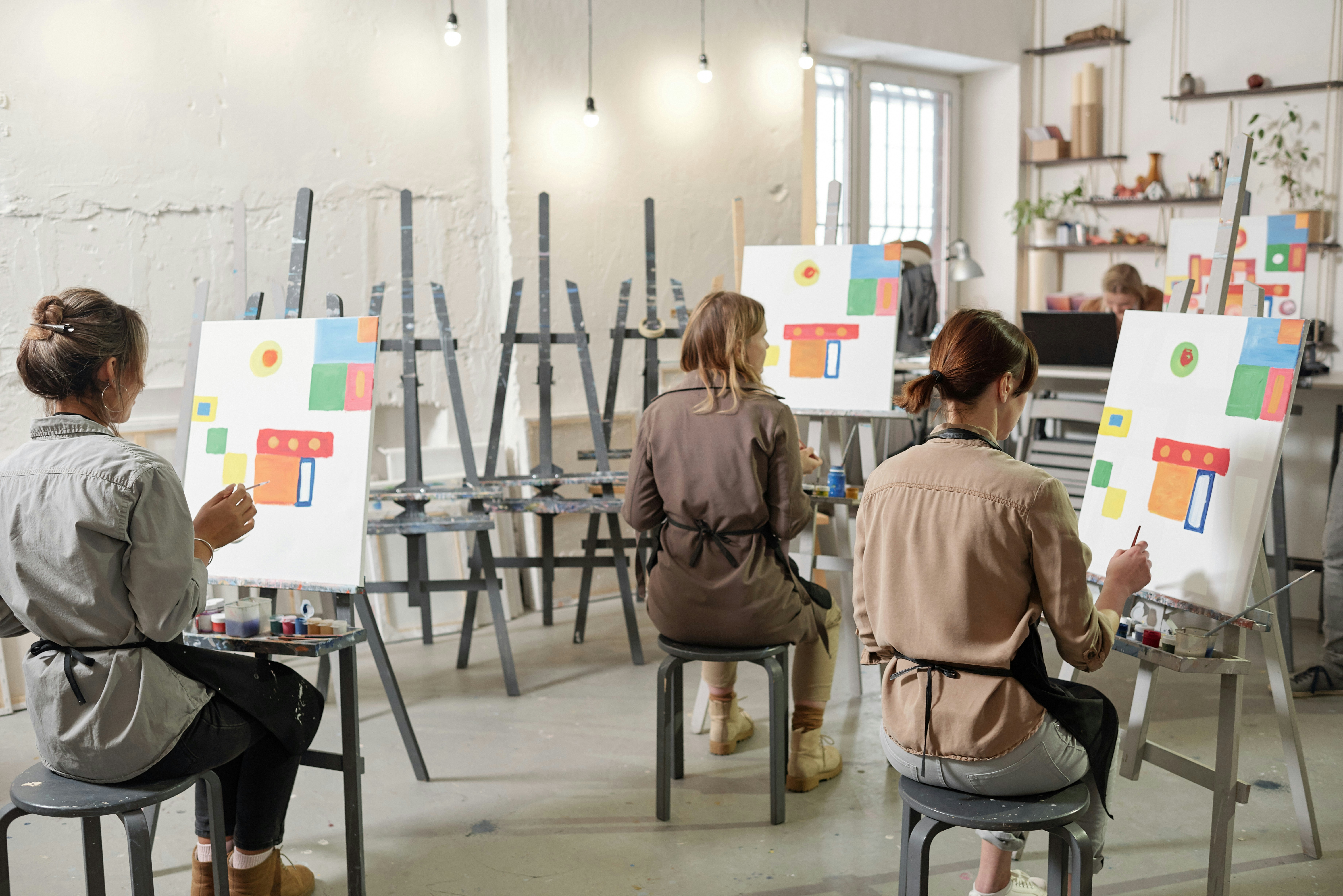 View of the backs of art students painting on canvases