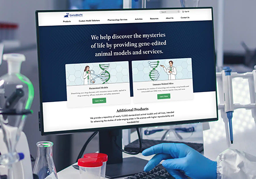 Monitor displaying a science website about gene-edited animal models on a lab bench, with a gloved hand and lab glassware nearby.