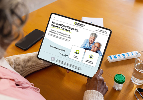 Person holds a tablet displaying a healthcare site about 'Personalized Shopping. Smart Choices.' on a wooden table.